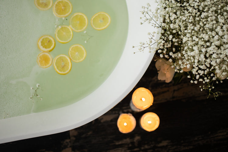 three candles burn beside a bubble bath