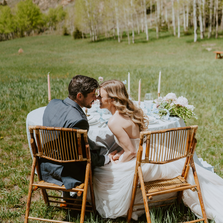 A couple canoodles at a beeswax candle laden wedding table