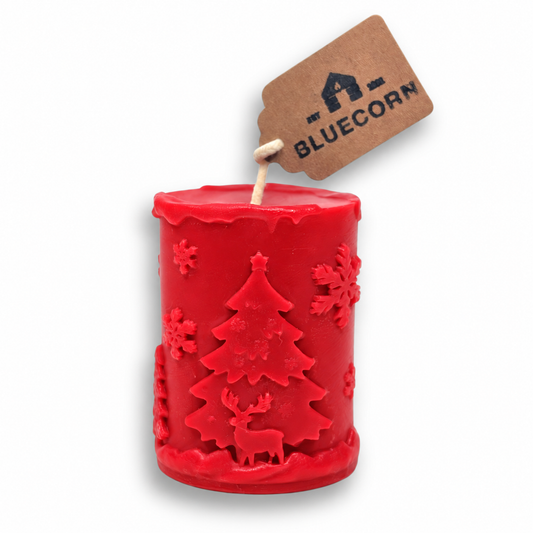 Bright red beeswax Christmas pillar candle with a raised winter scene of Christmas trees, reindeer and snowflakes.