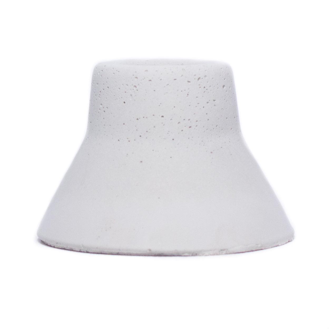 White concrete taper candle holder that measures 3" at the base and is 2" tall. Holder is shaped a bit like a suction cup, narrowing at the top to hold Bluecorn's standard beeswax taper candle.