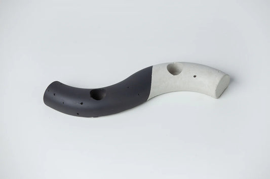 An S-shaped concrete taper candle holder with a gray body and a yellow tip, crafted from high-quality concrete.