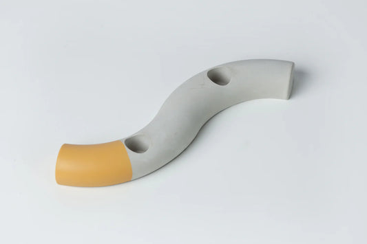 An S-shaped concrete taper candle holder with a gray body and a yellow tip, crafted from high-quality concrete.