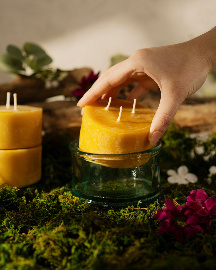 dropping a bluecorn beeswax 3-wick 10oz candle refill into its handmade glass
