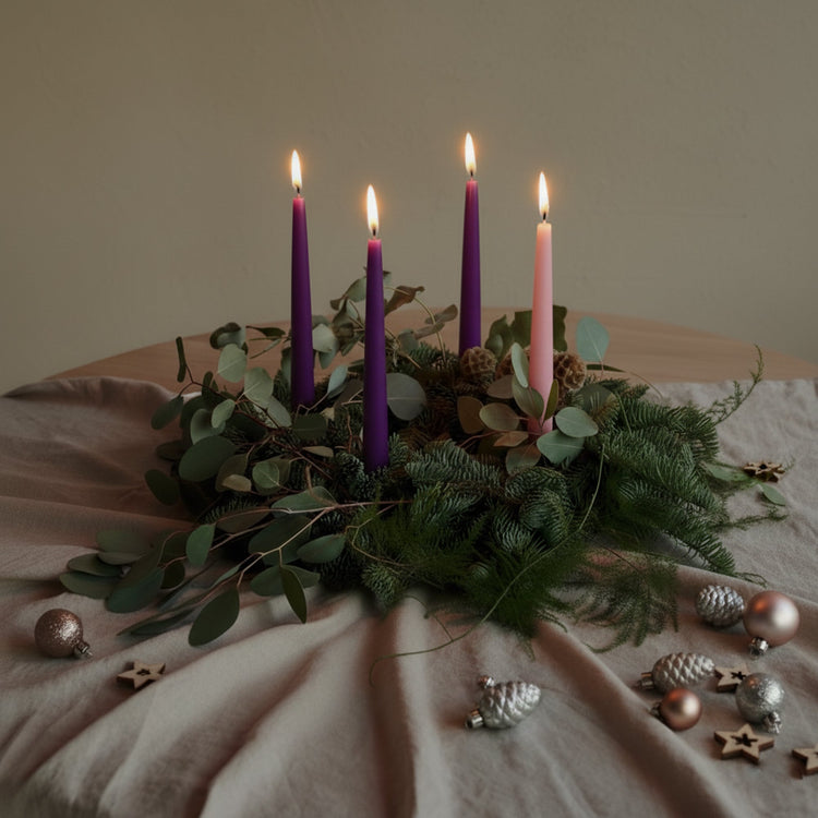 Advent candles burning in advent wreath on tablespace with greenery