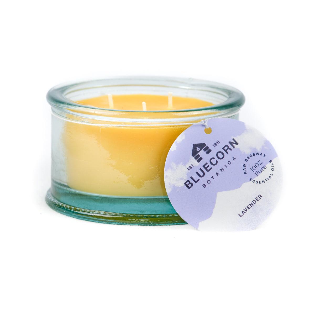 Bluecorn Botanica 100% Pure Beeswax Lavender 10oz 3-Wick Glass Candle. Wax is golden in color and glass is clear colored, with a white back drop. Features purple Bluecorn Botanica hang tag printed on 100% recyled paper with Bluecorn name and logo. Burn Time: 18 hours.  Made with 100% Pure Beeswax, 100% Pure Essentail Oils and a 100% pure cotton wick, no lead. Candles are paraffin free, clean burning and non-toxic. 
