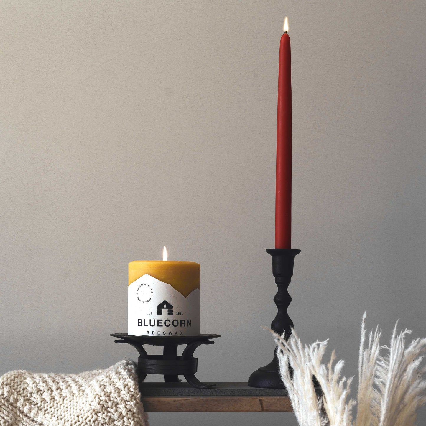 burgundy taper candle next to bluecorn beeswax pillar