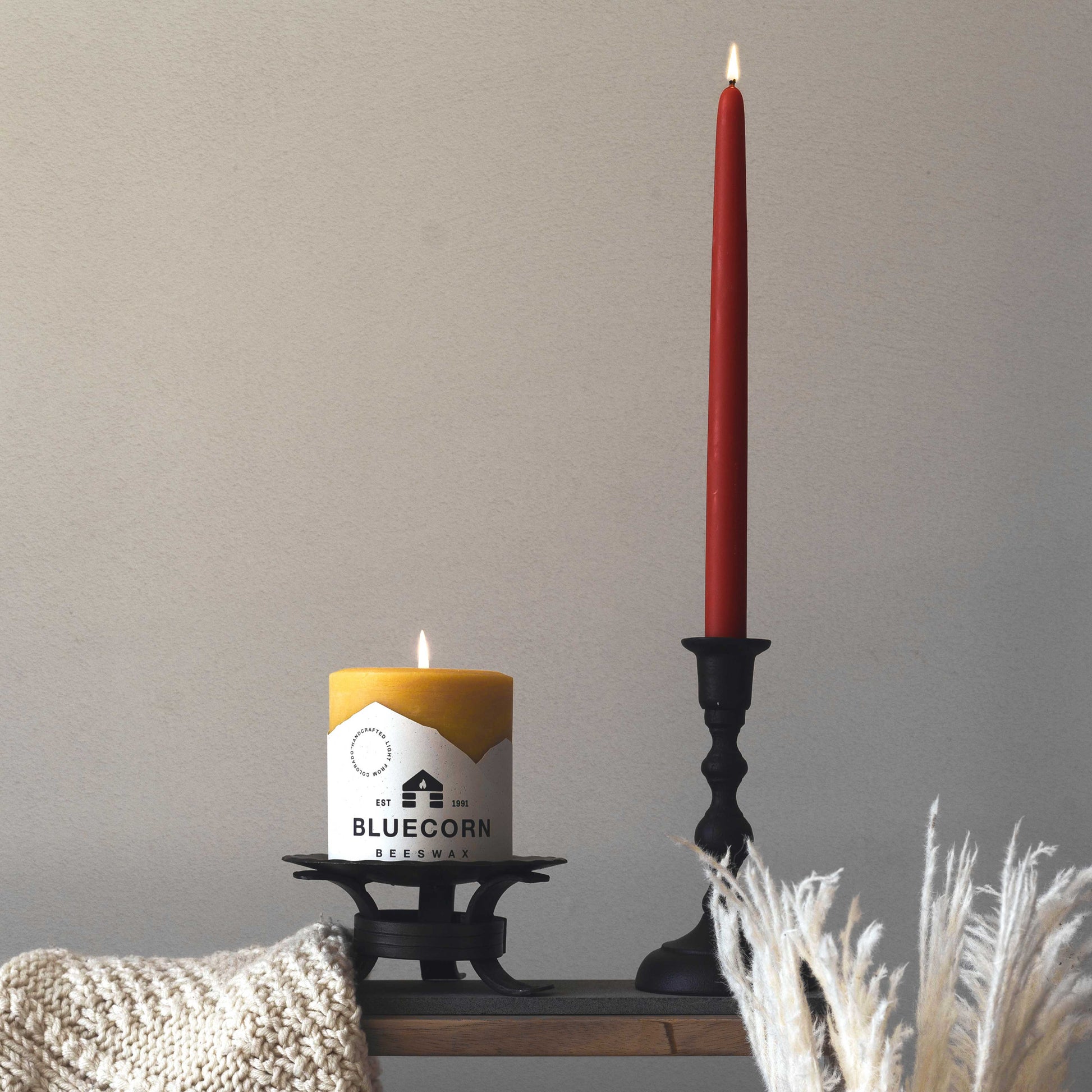 burgundy taper candle next to bluecorn beeswax pillar