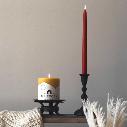 burgundy taper candle next to bluecorn beeswax pillar