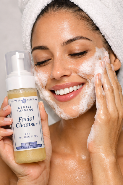 Woman applying facial cleanser to her face with a bottle of Power & Repair Gentle Foaming Facial Cleanser.