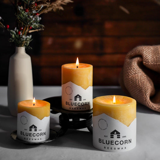 Glow Trio beeswax pillar candles lit together on a holiday table