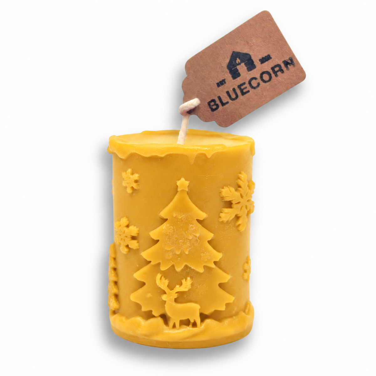 Raw golden beeswax Christmas pillar candle, unscented, with a raised winter scene of Christmas trees, reindeer and snowflakes.