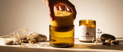 dropping pure beeswax refill candle into its blown glass candle holder with bluecorn beeswax logo in background