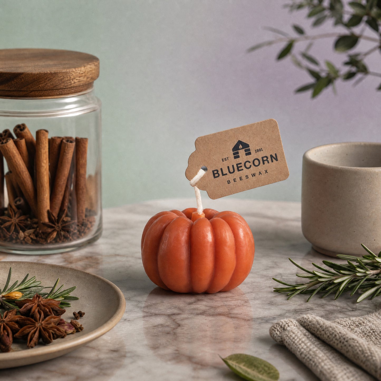 Orange beeswax pumpkin shaped candle, 4 inches wide, on an autumn table