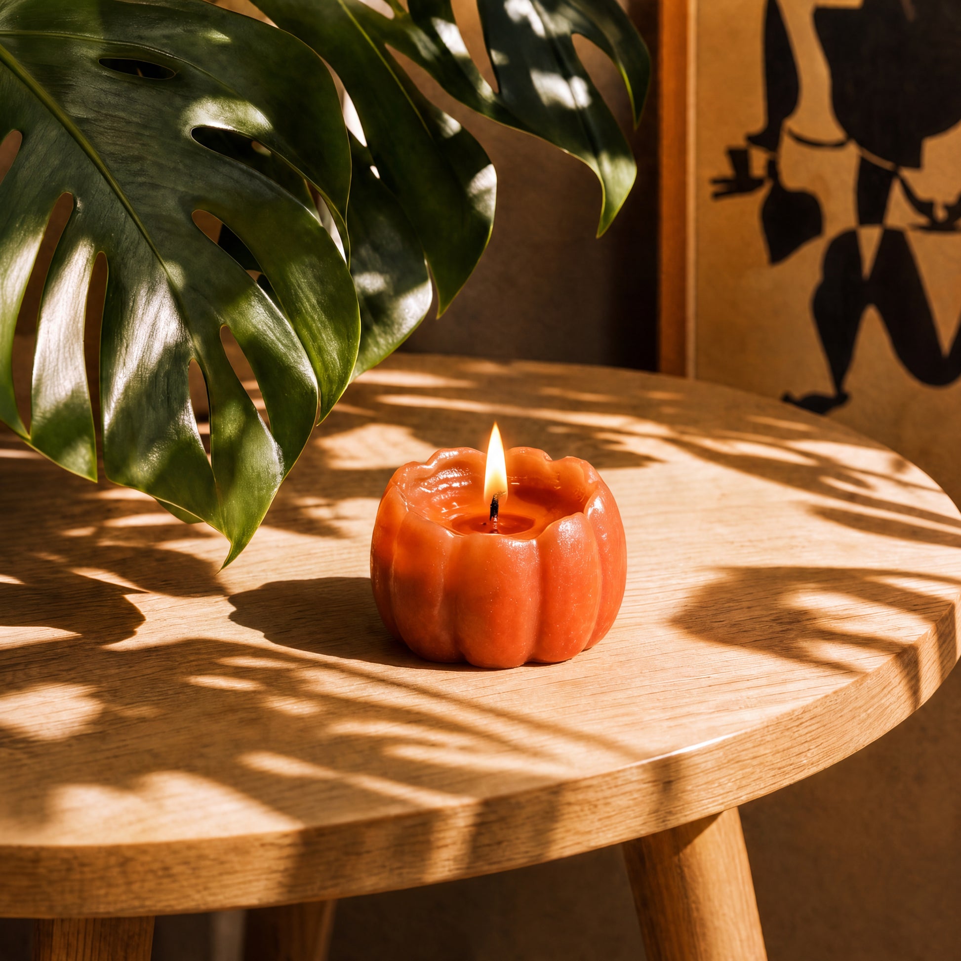 Lit beeswax pumpkin shaped candle glowing on an autumn table