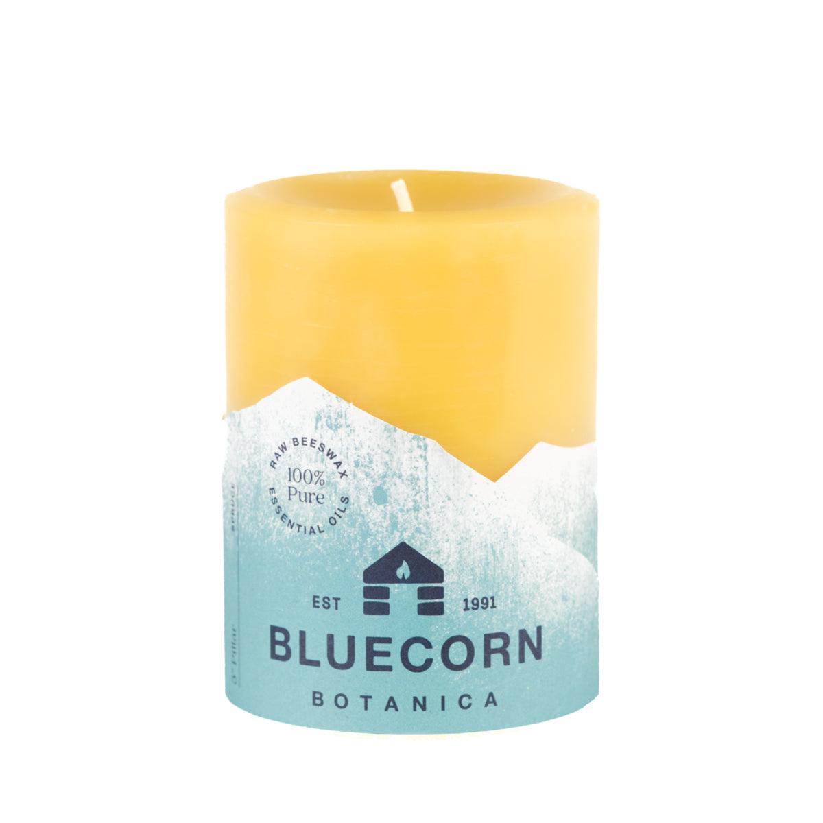 Bluecorn Botanica 100% Pure Beeswax Spruce 3" x 4"  Scented Pillar Candle. Burn Time: 60 hours. Made with 100% Pure Beeswax, 100% Pure Essential Oils, and a 100% pure cotton wick, no lead. Candles are paraffin free, clean burning and non-toxic. Features Bluecorn Botanica label in Forest Green printed on 100% recycled paper. Wax is golden in color. 