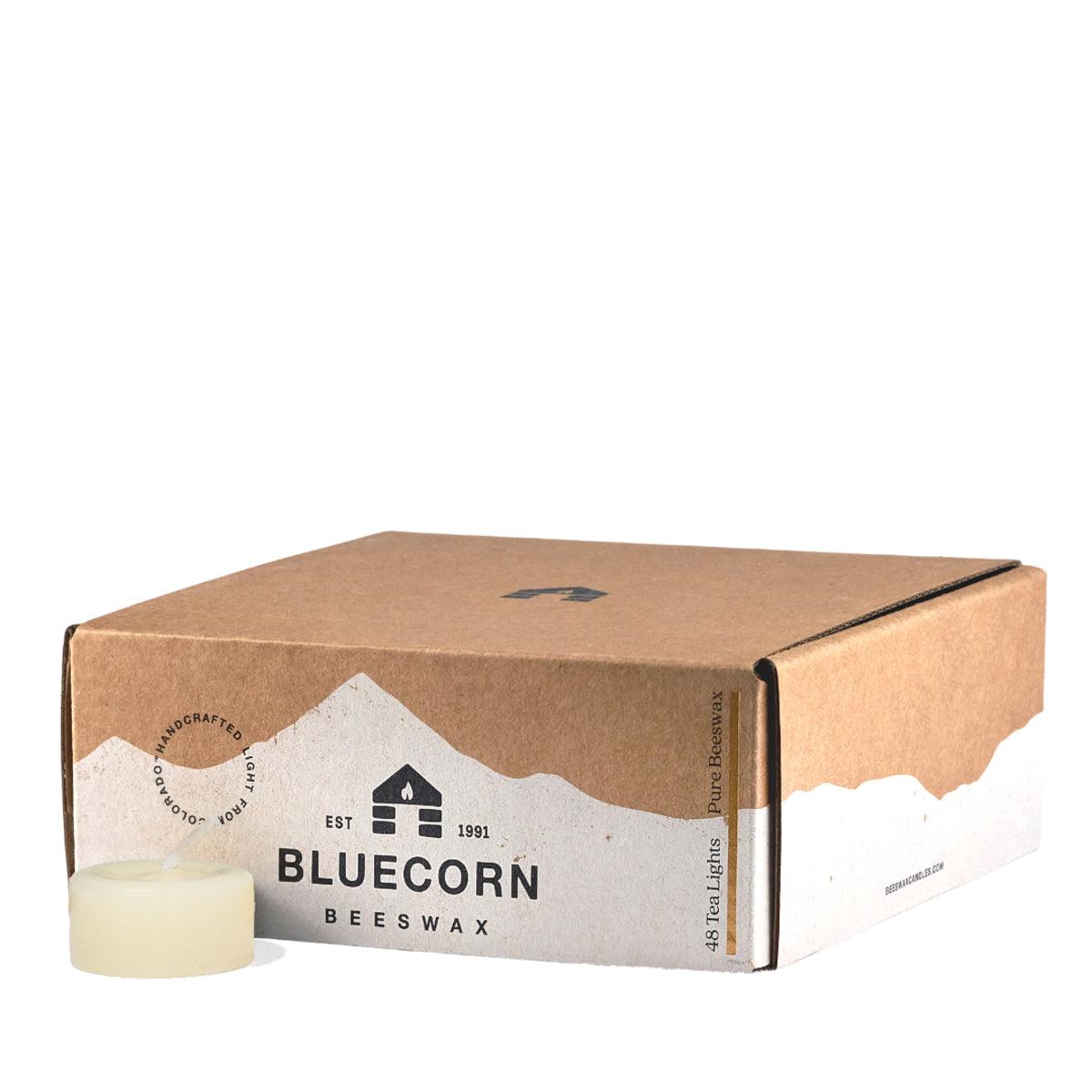 Bluecorn Beeswax 100% Pure Beeswax 48 Pack Ivory Tea Light Refill. Picture features one Tea Light outside of Bluecorn branded Tea Light Box with a white background. Box features Bluecorn Beeswax name and logo, with an outline of Mt. Wilson in white printed on a 100% recycled kraft paper box. Tea lights will burn for about 5 hours each.