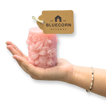 Dusty Rose Sculpted Floral Design Beeswax Pillar Candle with white background with a hand holding it to show size