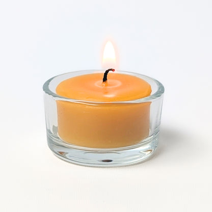 Yellow candle in a clear glass holder on a white background