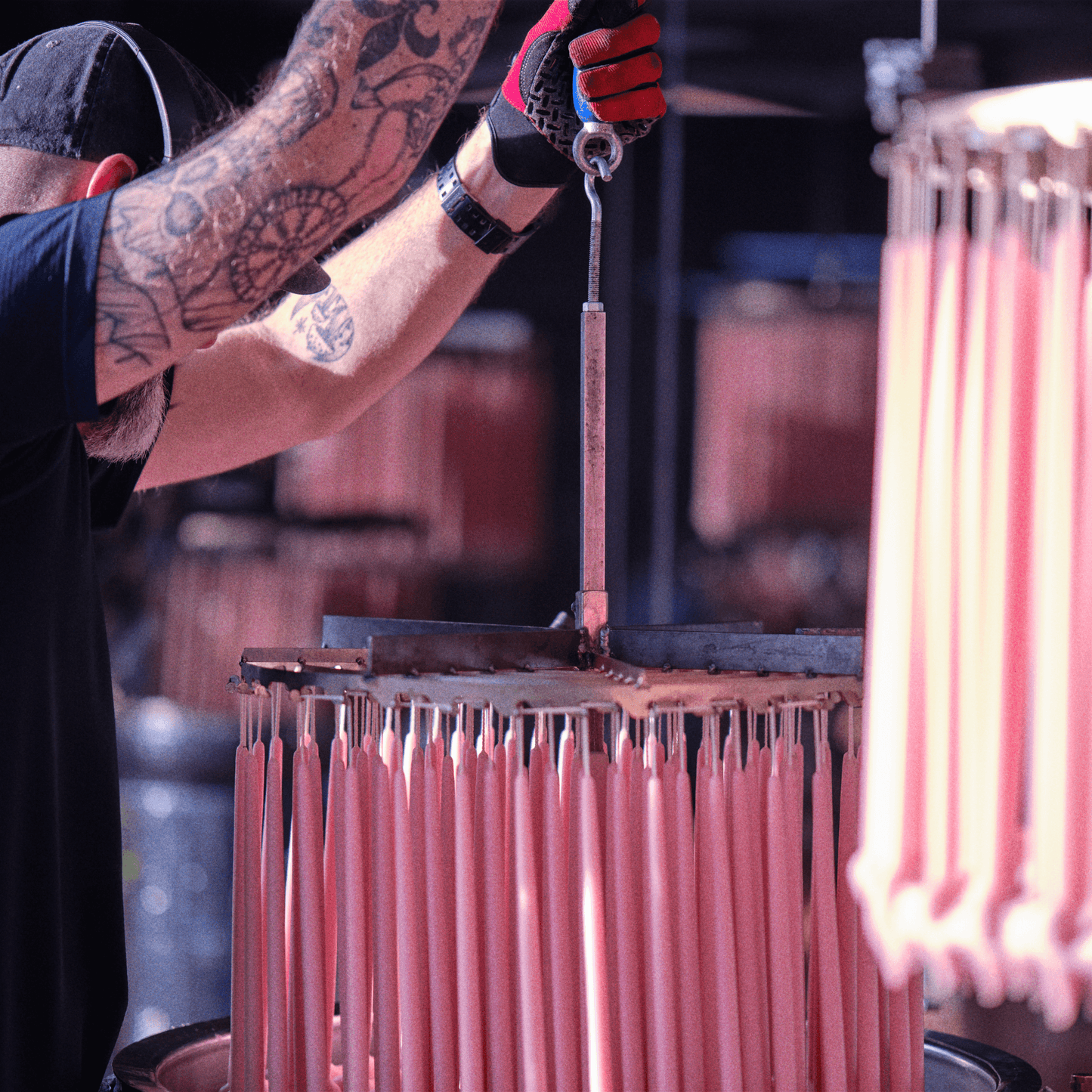 A craftsman dips pink candlesticks made from pure beeswax for Bluecorn Candles