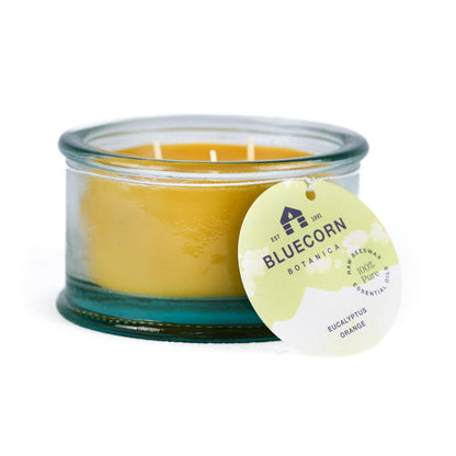 Bluecorn Botanica 100% Pure Beeswax Eucalyptus & Orange 10oz 3-Wick Glass Candle. Wax is golden in color and glass is clear colored, with a white back drop. Features lime green Bluecorn Botanica hang tag printed on 100% recyled paper with Bluecorn name and logo. Burn Time: 18 hours.  Made with 100% Pure Beeswax, 100% Pure Essentail Oils and a 100% pure cotton wick, no lead. Candles are paraffin free, clean burning and non-toxic. 