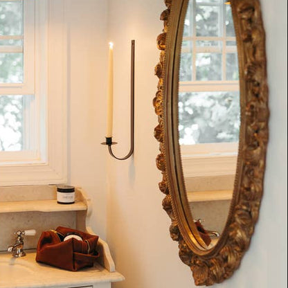 iron wall sconce with a glowing beeswax tapers for candles in wall-mounted sconce