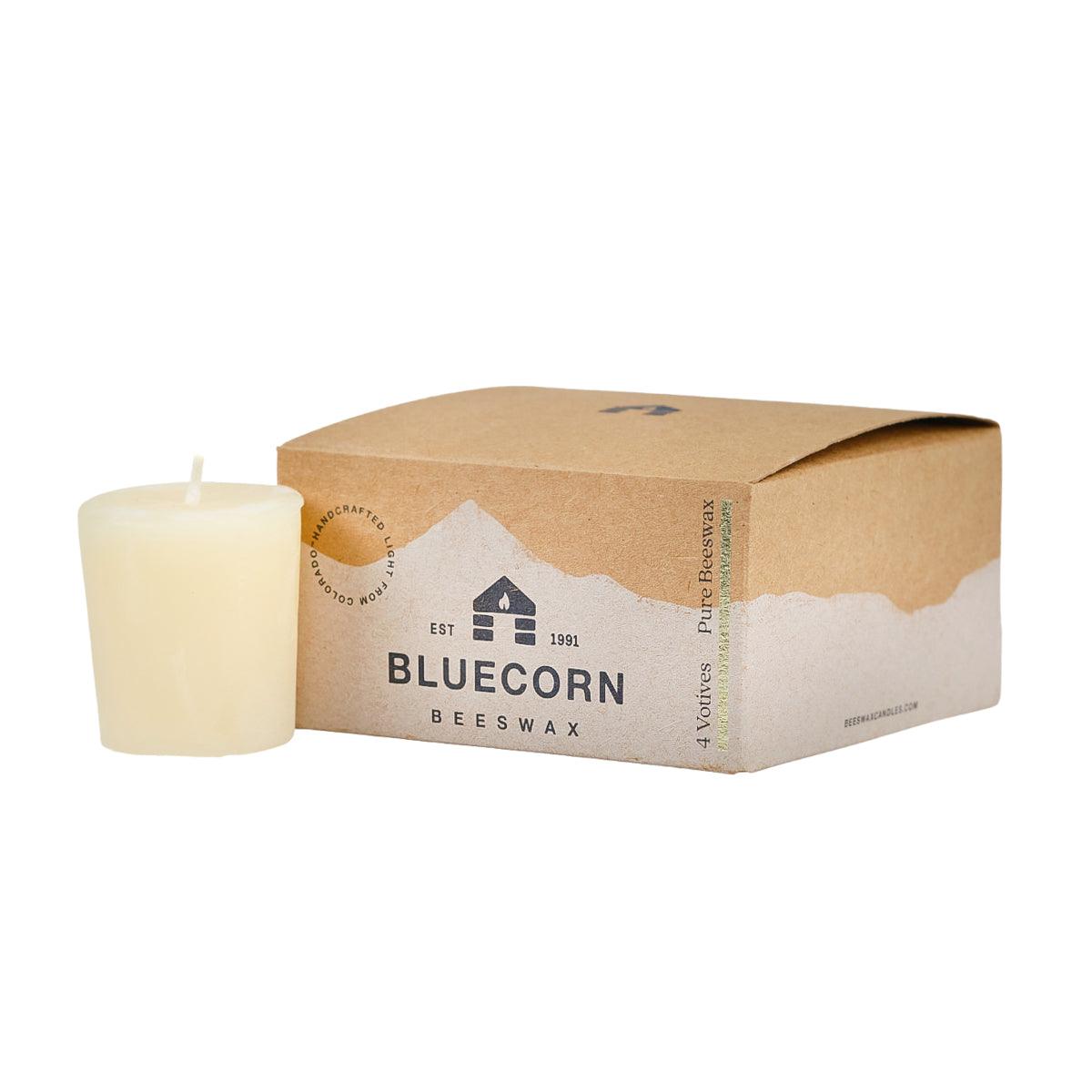 A single beeswax votive in the color ivory, sitting next to a closed 4-pack votive box