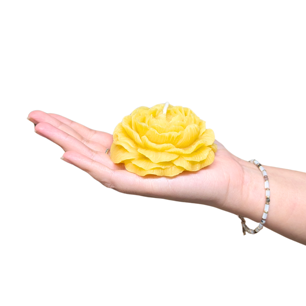 Raw peony shaped candle being held in a hand to show size