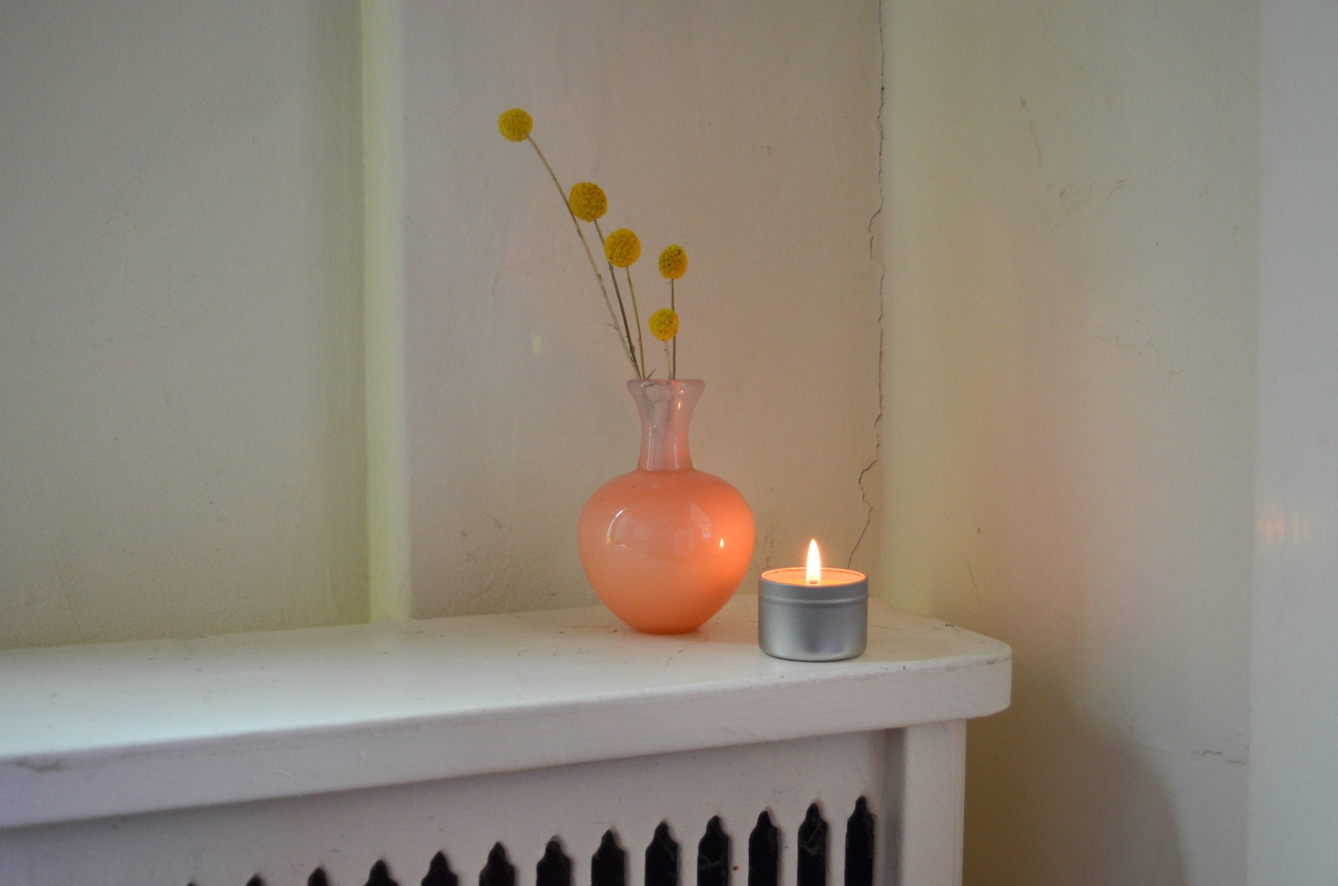 Lit Bluecorn Beeswax Raw Travel Tin Candle with pink vase.